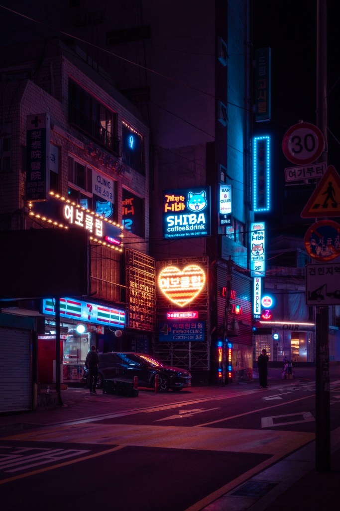An image of a moonlit street corner with neon signs in Itaewon, South Korea.